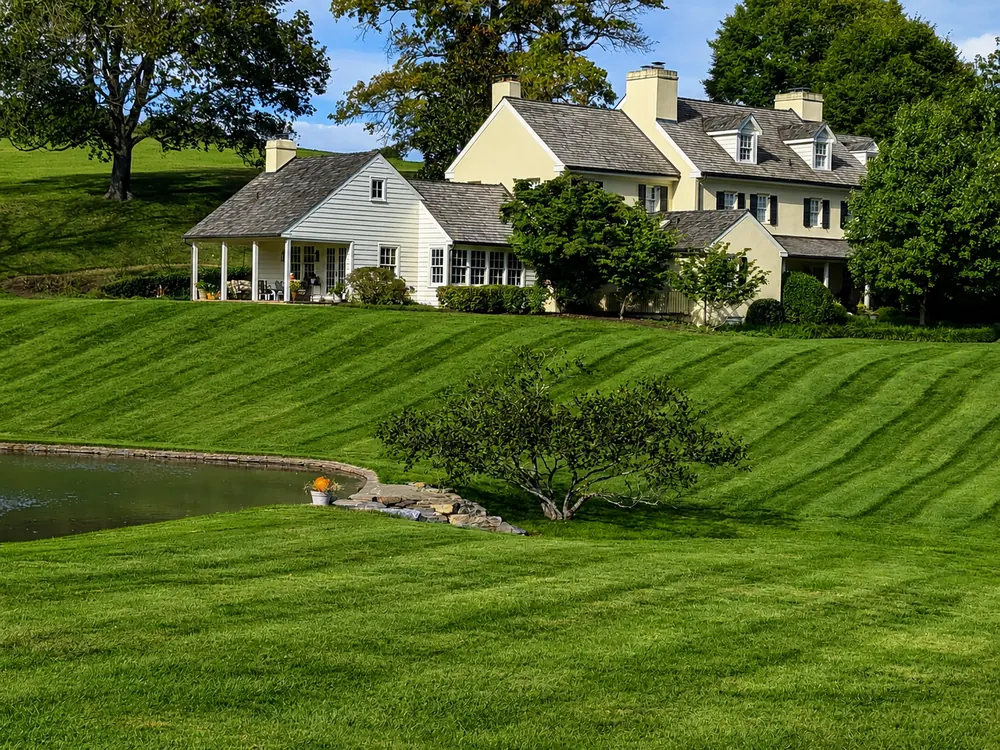 Estate property with a sweeping striped lawn beside a pond