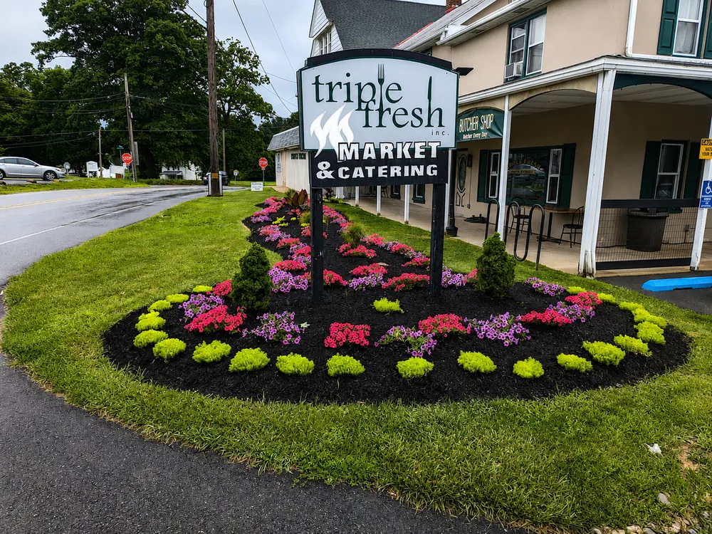Bright seasonal flower bed with fresh mulch around a property sign