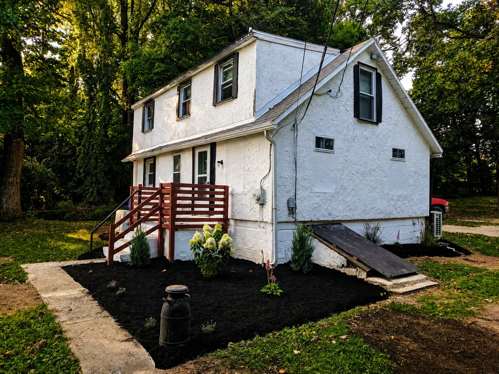 Fresh dark mulch installed in a new front bed at a white house
