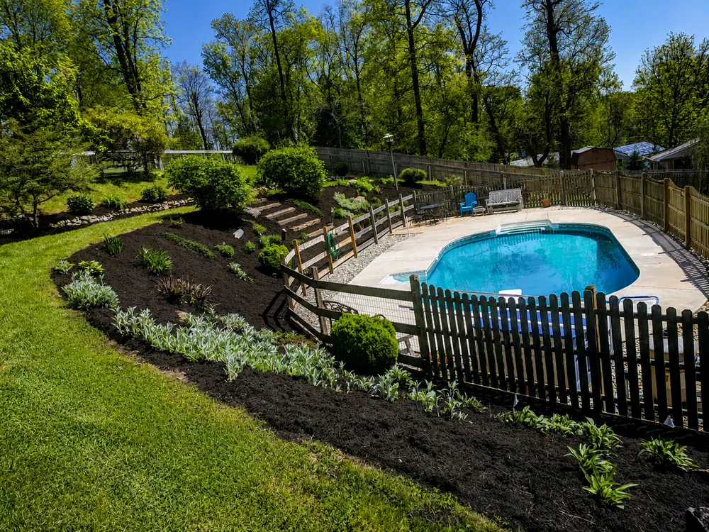 Landscaped planting beds and fresh mulch surrounding a backyard pool